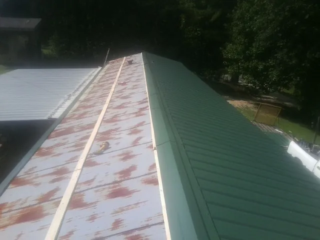 Old rusted panels beside newly installed green metal roofing — Wind Damage Roof Repair by Roofing Brothers in La Verne