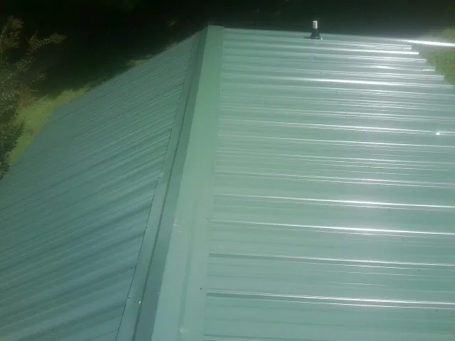 New green metal panels meeting at the ridge of a roof — Flat Roof Repair work by our crew in La Verne
