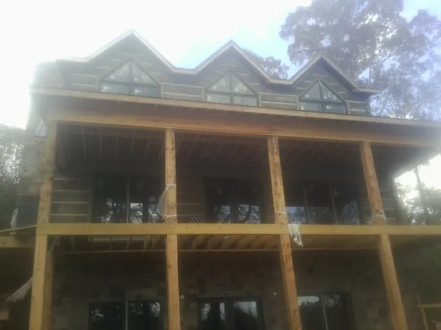Dormers and porch framing on a large log home under construction — Roof Coating work by our crew in La Verne