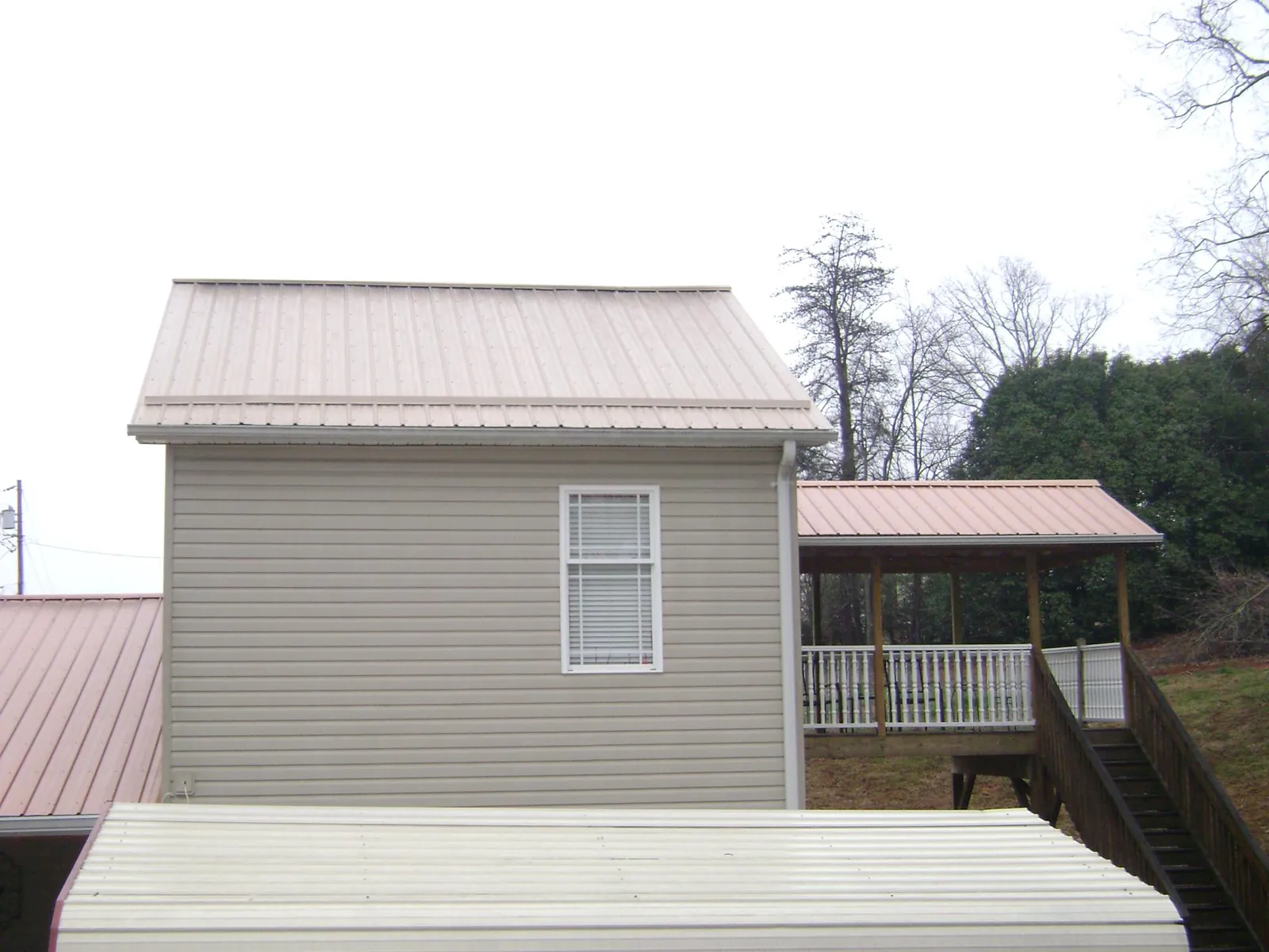Tan metal roofs on a two story addition and attached porch, from a Roof Replacement job in La Verne